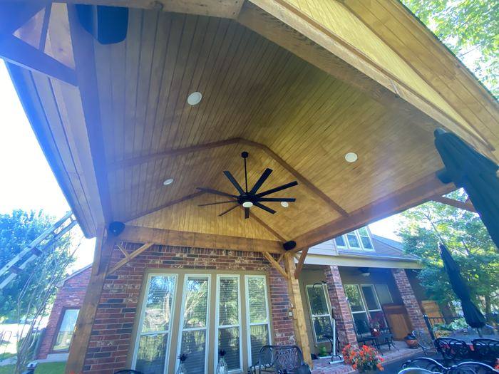 Covered patio ceiling with stained wood, recessed lights and a fan